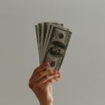 A hand holding out a fan of banknotes