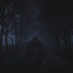 A lone figure on a dark misty forest path