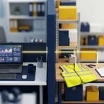 Tilt-shift view of an office desk running an analytics dashboard and a warehouse bench with a hi-vis vest and hard hat, separated by a partition, with a single lit line running across the divide