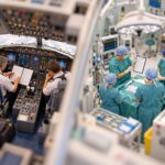 Tilt-shift miniature of a small aircraft cockpit crew and a surgical team working through printed checklists side by side